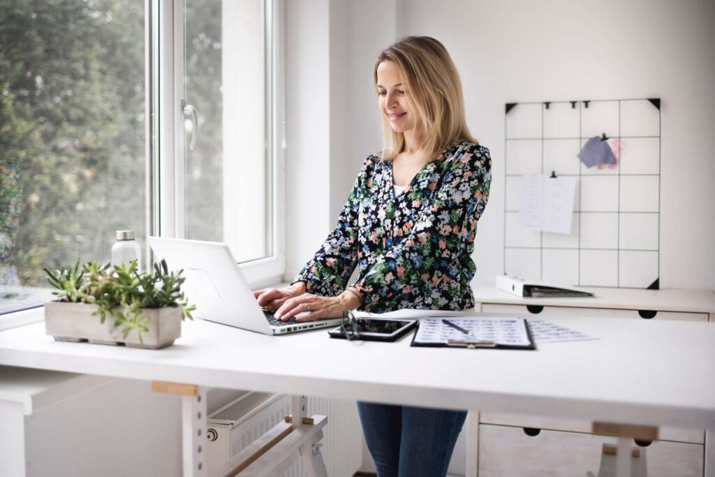 side-view-adult-female-working-from-home-with-sit-stand-desk